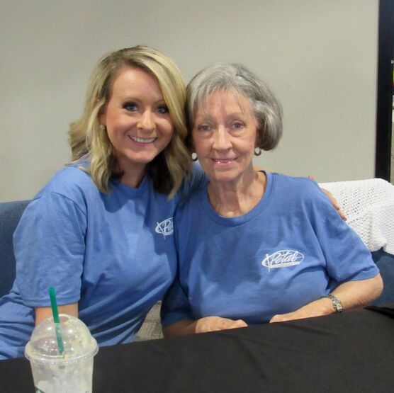 Two volunteers smile proudly for a photo as they wait for families to receive uniforms.